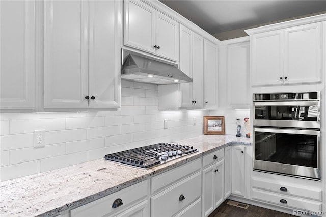 4475 Hidden Gulch Rd, Castle Rock, CO 80104 - kitchen featuring under cabinet range hood, appliances with stainless steel finishes, white cabinetry, backsplash, and dark wood-style flooring