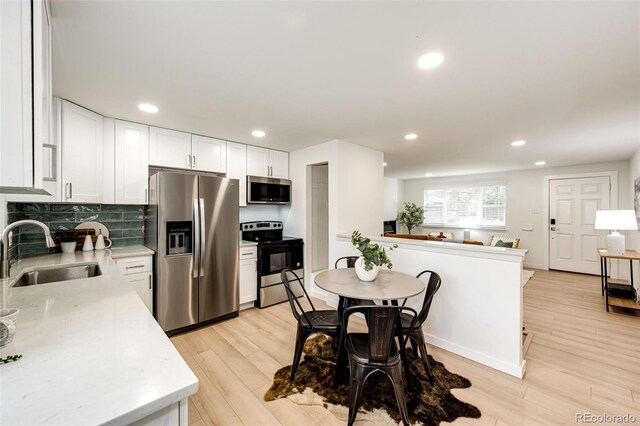 5780 W 5th Ave, Lakewood, CO 80226 - kitchen with stainless steel appliances, white cabinets, light wood finished floors, decorative backsplash, and recessed lighting