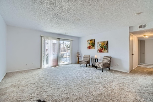 sitting room featuring light colored carpet and a textured ceiling