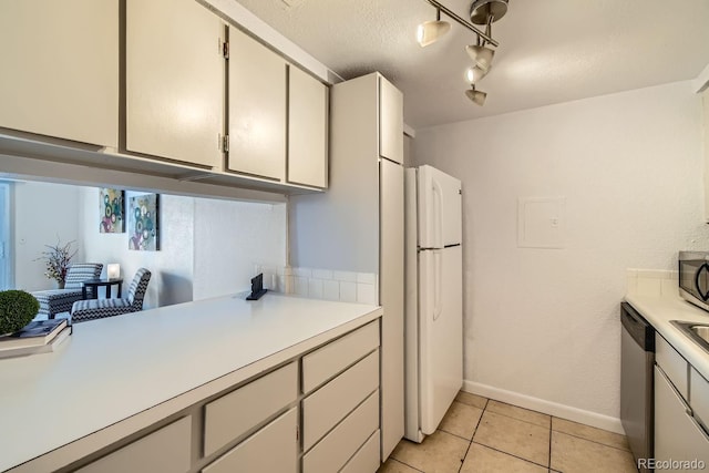 kitchen with rail lighting, a textured ceiling, light tile patterned floors, stainless steel appliances, and white cabinets