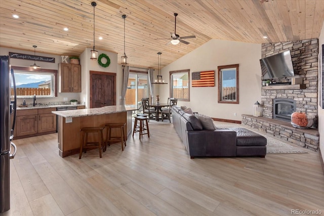living area with plenty of natural light, a fireplace, ceiling fan, and wooden ceiling