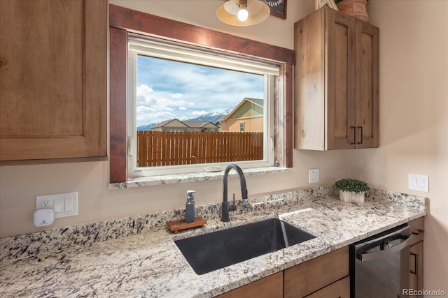 kitchen featuring light stone countertops, plenty of natural light, a sink, and dishwasher