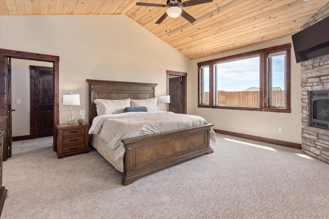 bedroom with wooden ceiling, vaulted ceiling, a stone fireplace, and light carpet