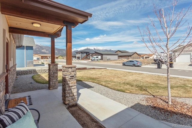 view of yard with covered porch, a residential view, and a mountain view