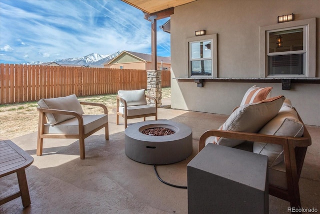 view of patio / terrace featuring an outdoor living space with a fire pit, a mountain view, and fence