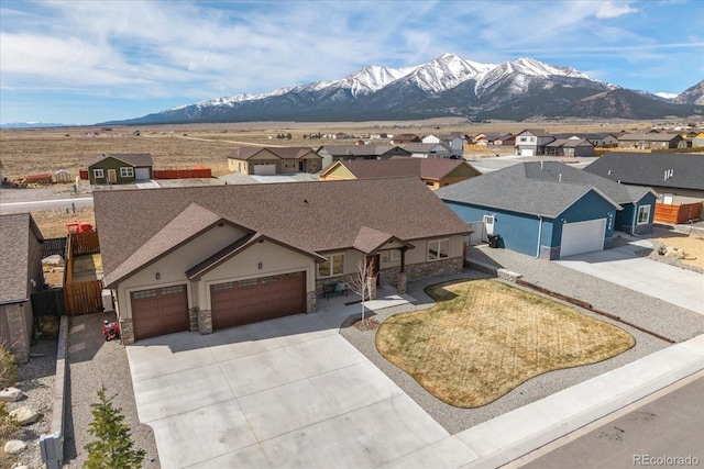 view of front of house with a mountain view, a residential view, stone siding, and driveway