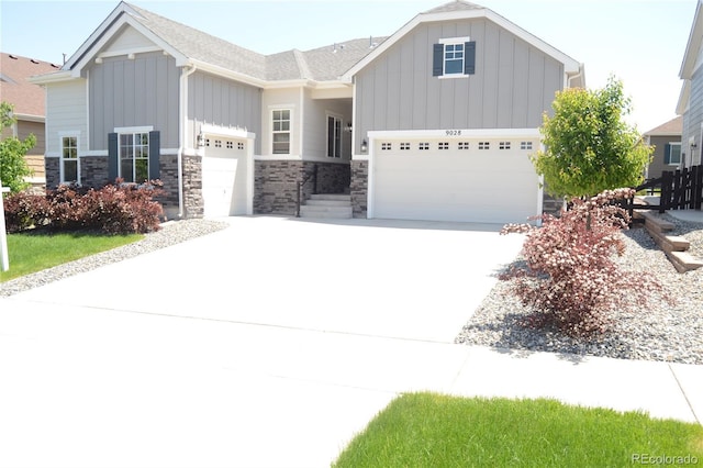 9028 S Catawba St, Aurora, CO 80016 - view of front of home with board and batten siding, concrete driveway, an attached garage, and stone siding