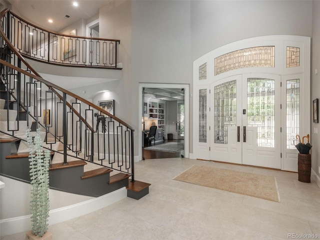 entryway featuring french doors, stairway, a towering ceiling, and baseboards