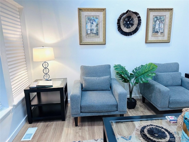 sitting room with wood finished floors, visible vents, and baseboards