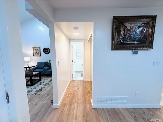 corridor with visible vents, light wood-type flooring, and baseboards