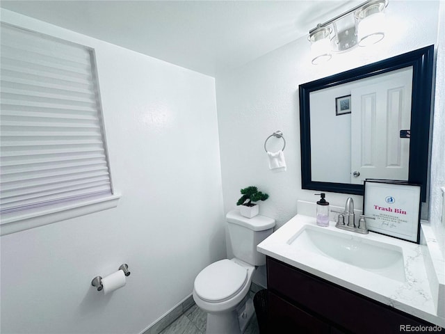 bathroom with toilet, vanity, and baseboards