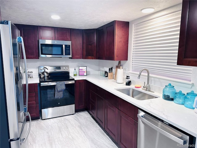 kitchen with a sink, stainless steel appliances, a textured ceiling, and dark brown cabinets