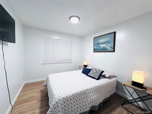 bedroom with baseboards and wood finished floors