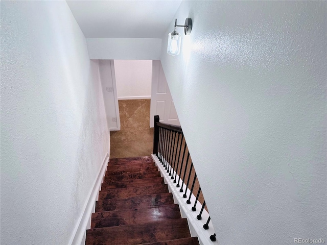 staircase with carpet, baseboards, and a textured wall