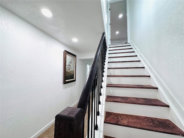 staircase featuring recessed lighting, carpet flooring, a textured wall, and baseboards