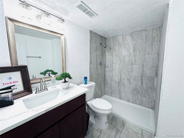 full bath with visible vents, tiled shower, a textured ceiling, toilet, and a textured wall