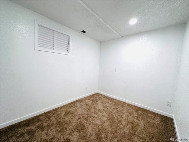 finished below grade area with visible vents, baseboards, a textured ceiling, and carpet flooring