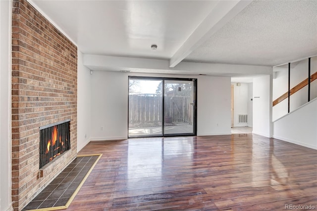 unfurnished living room featuring visible vents, a textured ceiling, a fireplace, and hardwood / wood-style flooring