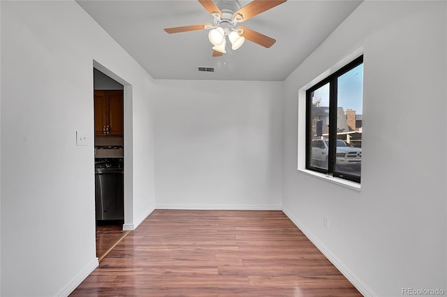 unfurnished room featuring a ceiling fan, wood finished floors, visible vents, and baseboards