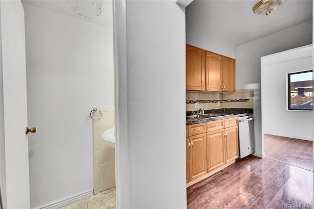 kitchen with a sink, dark countertops, decorative backsplash, dishwasher, and dark wood-style flooring