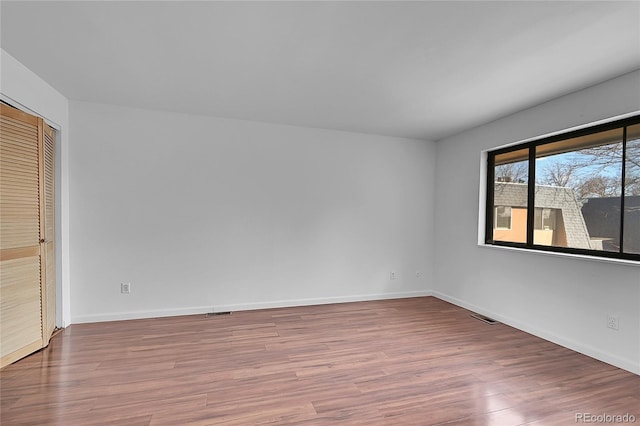 unfurnished bedroom featuring a closet, visible vents, baseboards, and wood finished floors