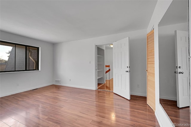 spare room with wood finished floors, visible vents, and baseboards