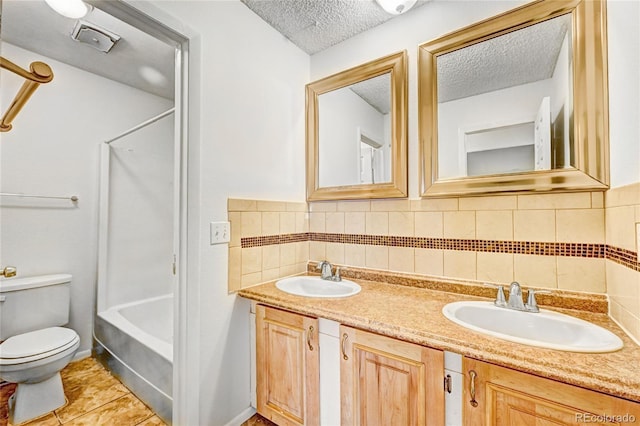 full bathroom featuring a sink, a textured ceiling, double vanity, and toilet