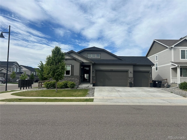 craftsman-style home with an attached garage, driveway, stone siding, and a front yard