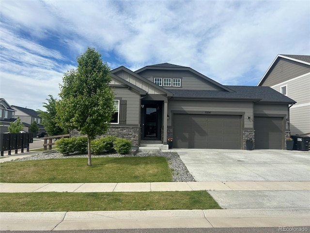 craftsman inspired home with an attached garage, driveway, a front lawn, and stone siding