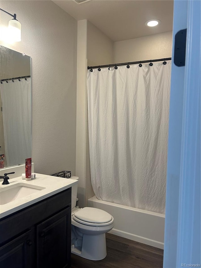 bathroom featuring wood finished floors, vanity, shower / bathtub combination with curtain, toilet, and recessed lighting