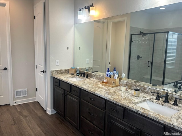 full bath featuring wood finished floors, a stall shower, and double vanity