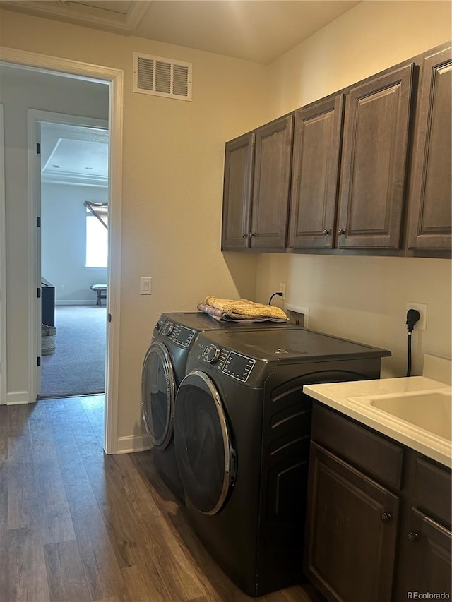 washroom with cabinet space, separate washer and dryer, dark wood finished floors, and baseboards
