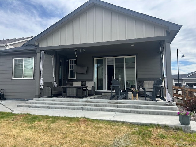 rear view of property featuring board and batten siding, a patio, and outdoor lounge area