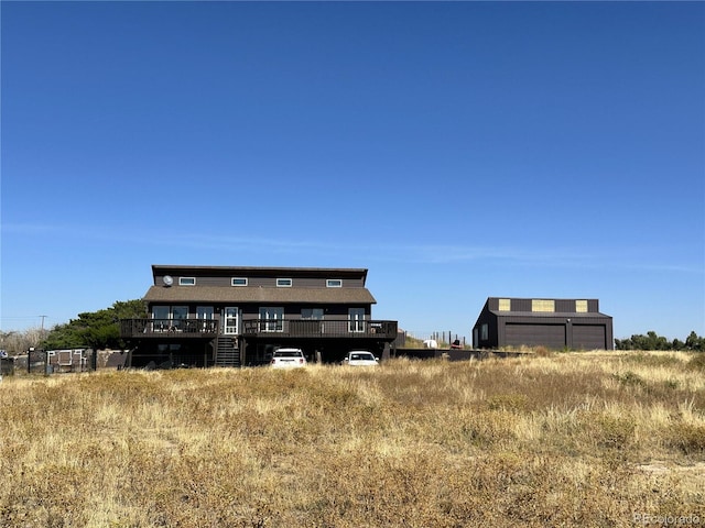 rear view of property featuring a rural view, a deck, and a garage