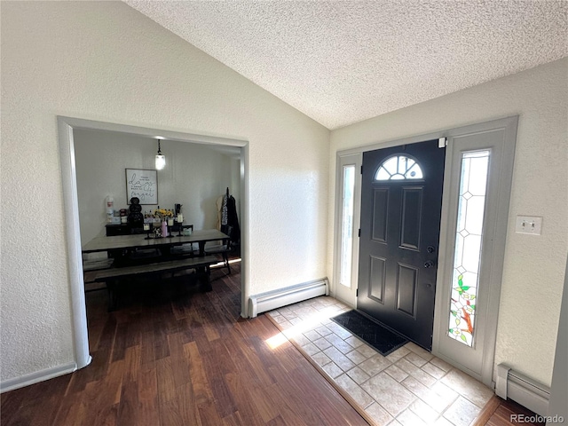 foyer entrance featuring vaulted ceiling, wood-type flooring, a textured ceiling, and a baseboard radiator