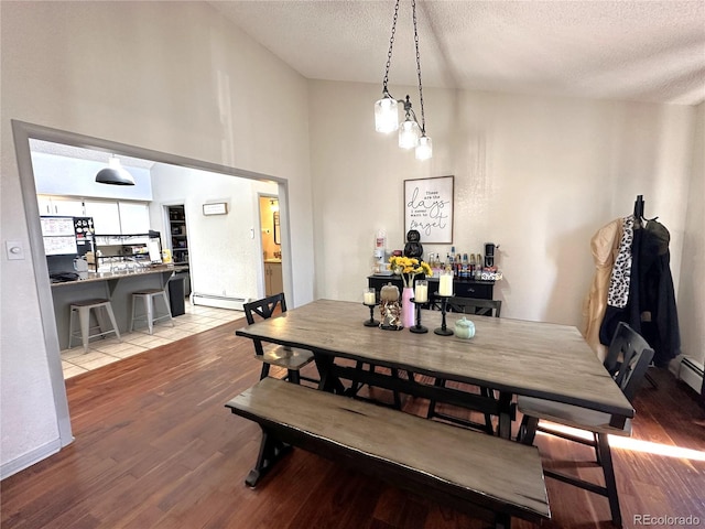 dining area featuring wood-type flooring, a textured ceiling, and a baseboard radiator