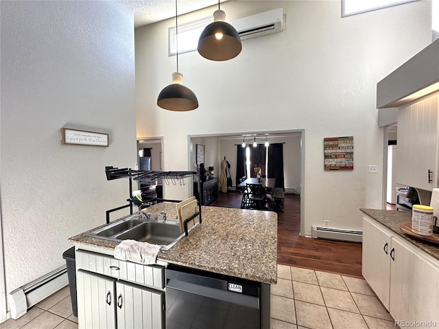 kitchen featuring hanging light fixtures, a baseboard radiator, black dishwasher, an AC wall unit, and light tile patterned floors