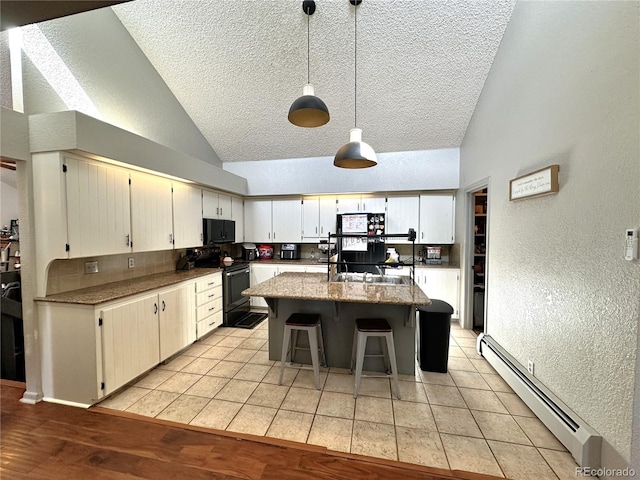 kitchen with pendant lighting, a center island, high vaulted ceiling, black appliances, and a baseboard radiator