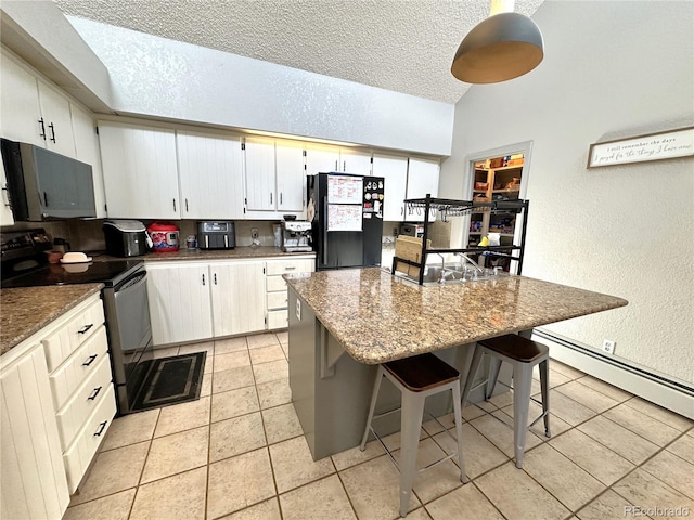 kitchen featuring black appliances, a center island, white cabinets, and a breakfast bar area