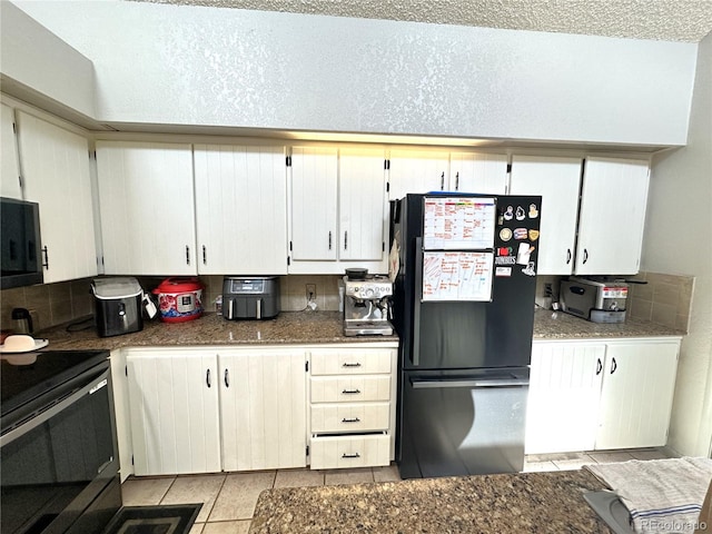 kitchen featuring white cabinets, light tile patterned floors, a textured ceiling, and black appliances