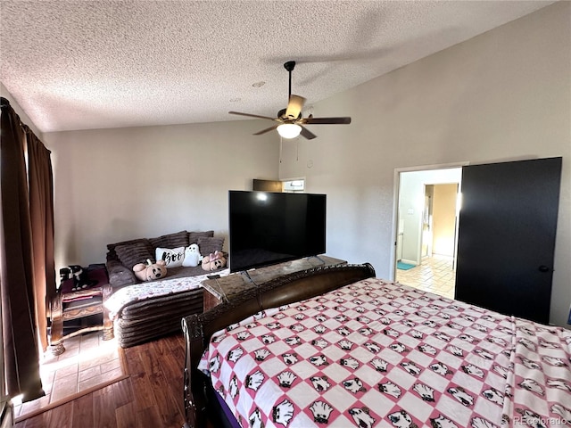 bedroom with a textured ceiling, ceiling fan, wood-type flooring, and lofted ceiling