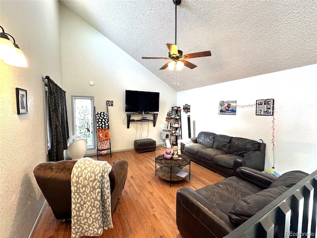 living room with ceiling fan, hardwood / wood-style floors, high vaulted ceiling, and a textured ceiling