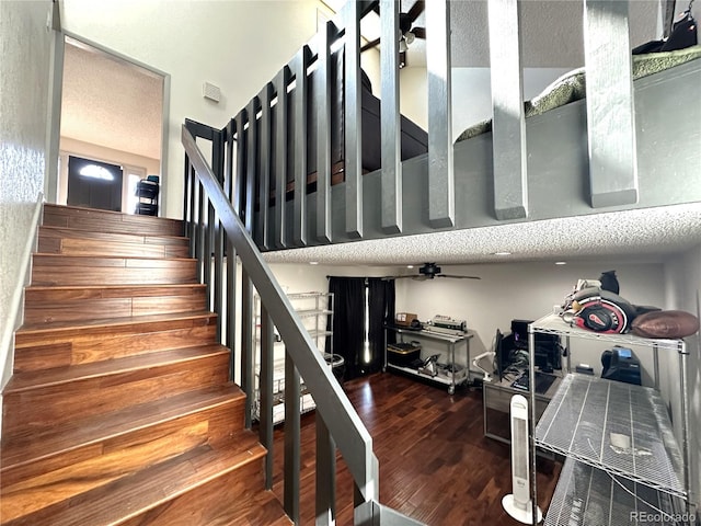 stairway with ceiling fan, hardwood / wood-style floors, and a textured ceiling