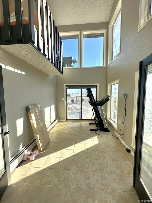 unfurnished living room with light tile patterned flooring, a textured ceiling, and a baseboard radiator