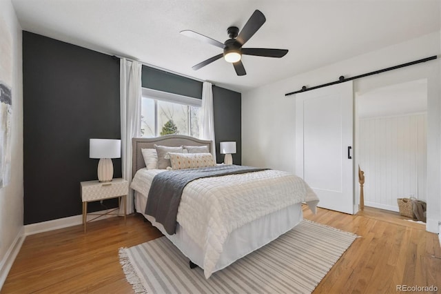 1610 Trenton St, Denver, CO 80220 - bedroom with a ceiling fan, a barn door, light wood-style floors, and baseboards