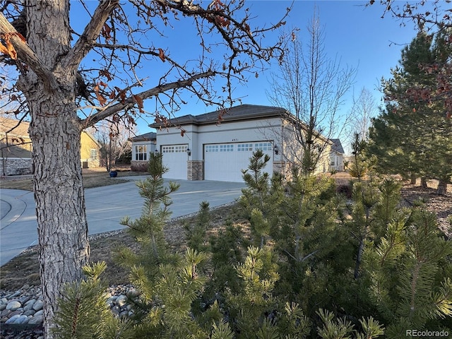 view of property exterior featuring a garage, stone siding, driveway, and stucco siding