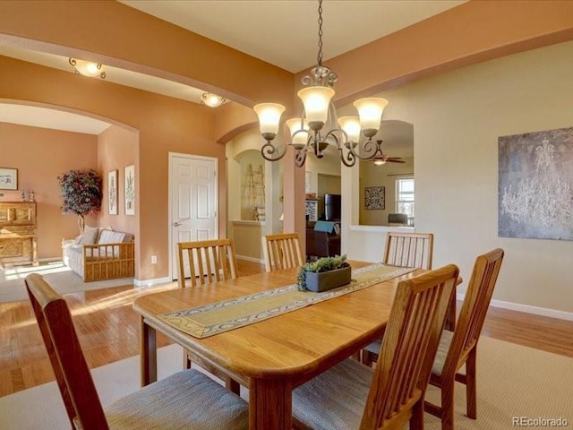 dining room featuring baseboards, arched walkways, and wood finished floors