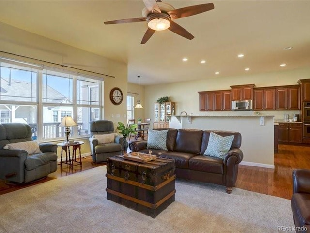 living area with a ceiling fan, recessed lighting, baseboards, and wood finished floors