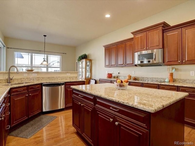 kitchen with stainless steel appliances, a kitchen island, light wood-type flooring, and a sink