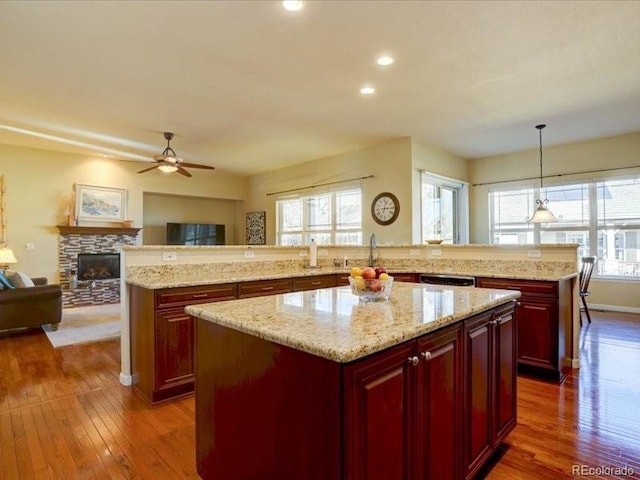 kitchen featuring reddish brown cabinets, a center island, open floor plan, and a wealth of natural light